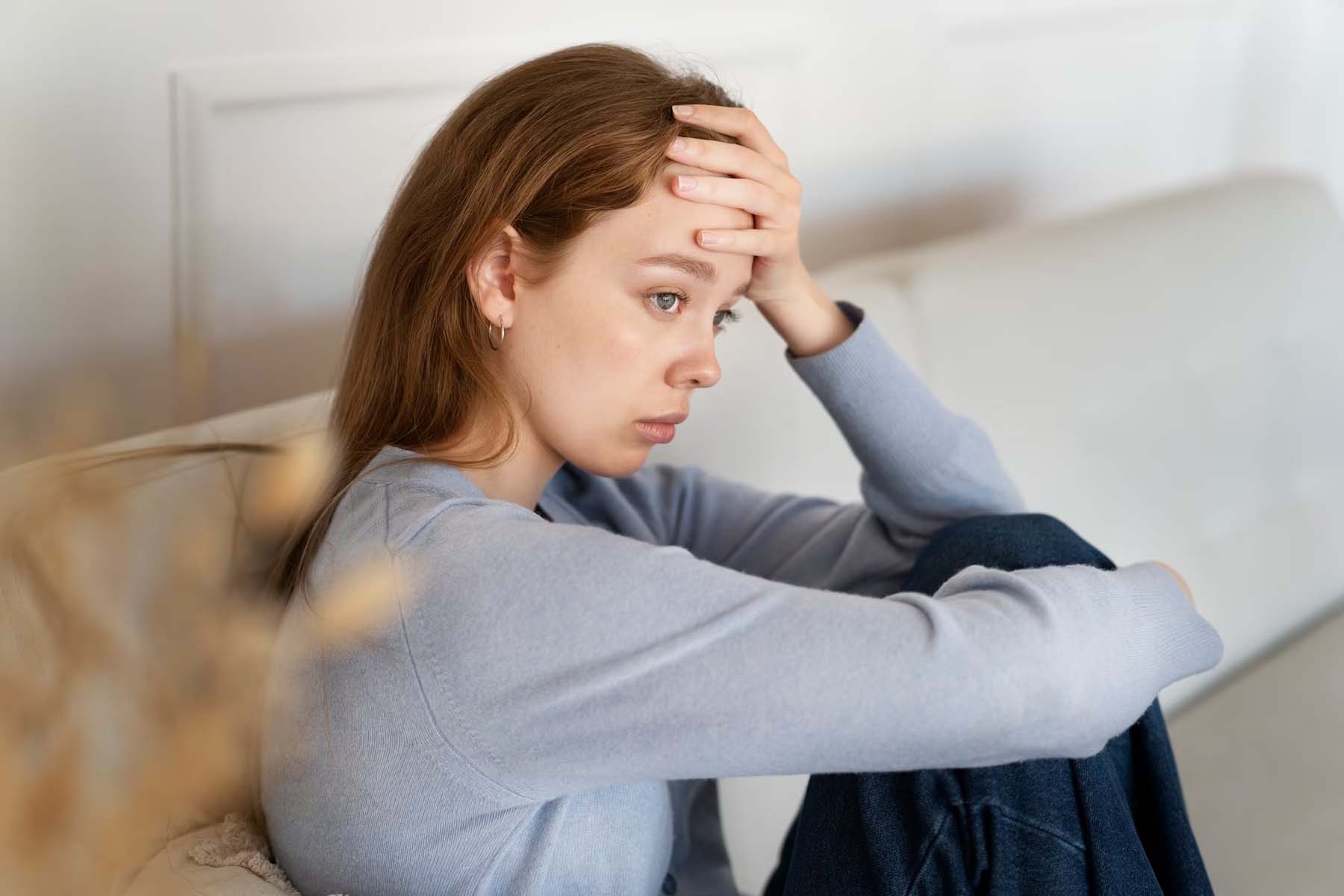 Anxious woman sitting on couch side view